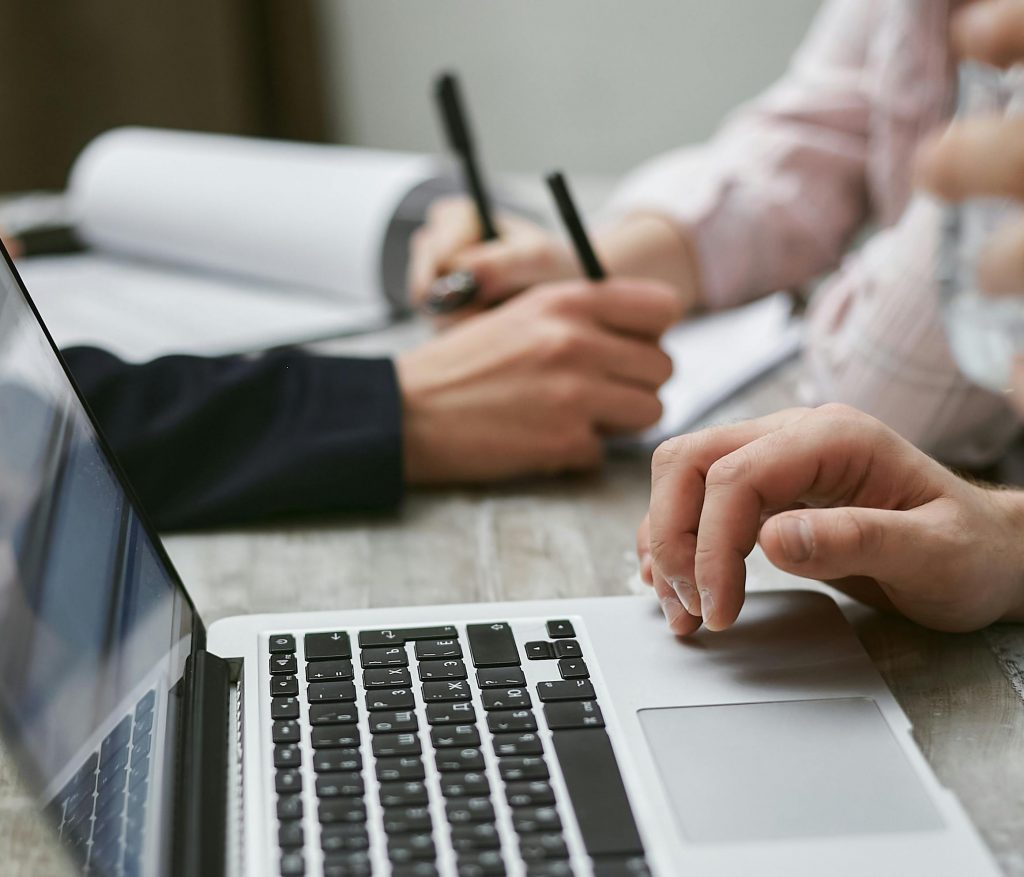 Hands-on teamwork over a laptop in a business meeting setting.